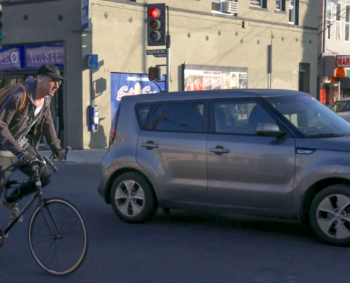 man on bicycle next to car on city street