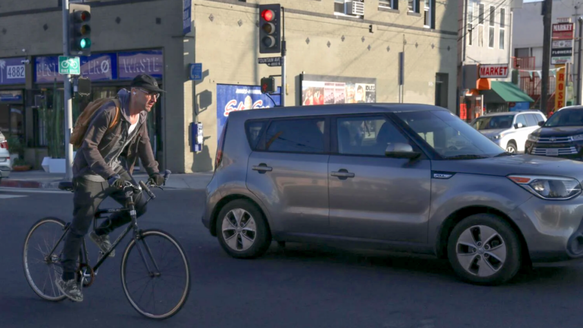 man on bicycle next to car on city street