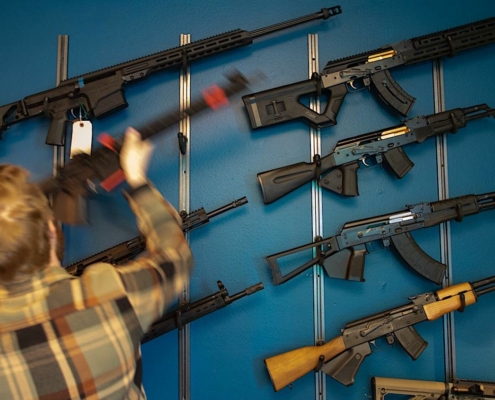 man facing wall lined with firearms for sale