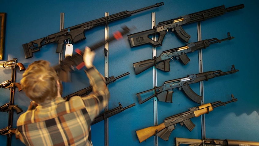 man facing wall lined with firearms for sale