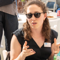 woman in sunglasses gestures while seated an event