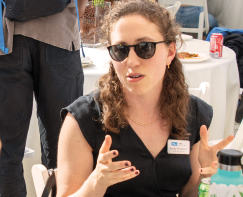 woman in sunglasses gestures while seated an event