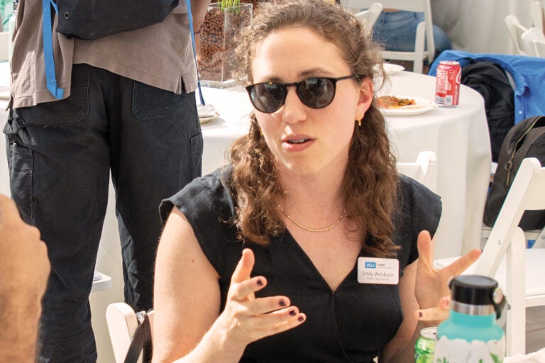 woman in sunglasses gestures while seated an event