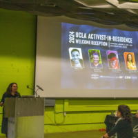 woman at podium with image projected on large screen behind her that shows activists' pictures and names