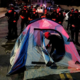 Man setting up tent in street in front of police officers