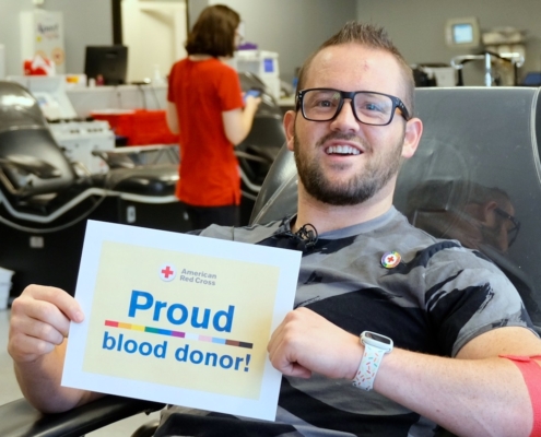 man in glasses with sign that says Proud blood donor