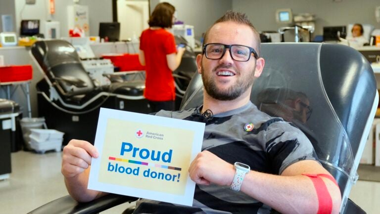 man in glasses with sign that says Proud blood donor