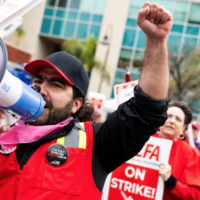 Picket line with man in red vest with megaphone in front