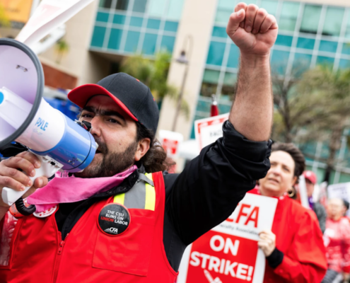 Picket line with man in red vest with megaphone in front