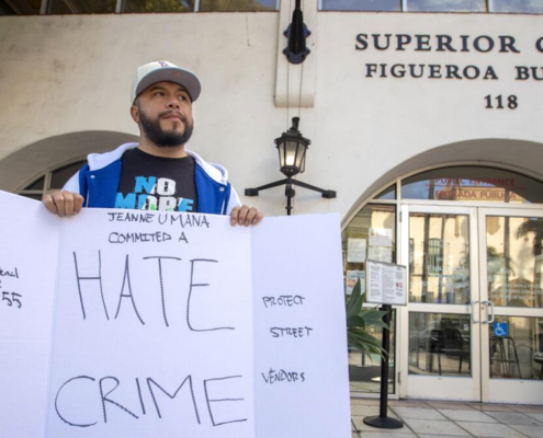 Man in hat holding sign that says "Hate Crime"