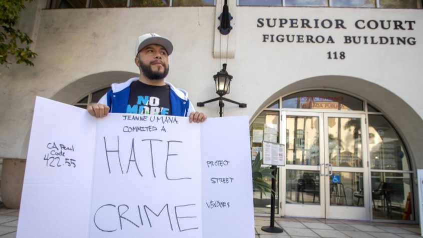 Man in hat holding sign that says "Hate Crime"