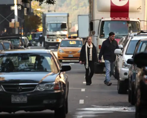 people and cars on busy street