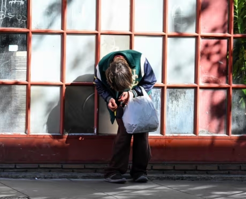 a person holding a shopping bag slumps forward in front of a multipane window