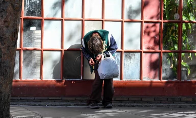 a person holding a shopping bag slumps forward in front of a multipane window
