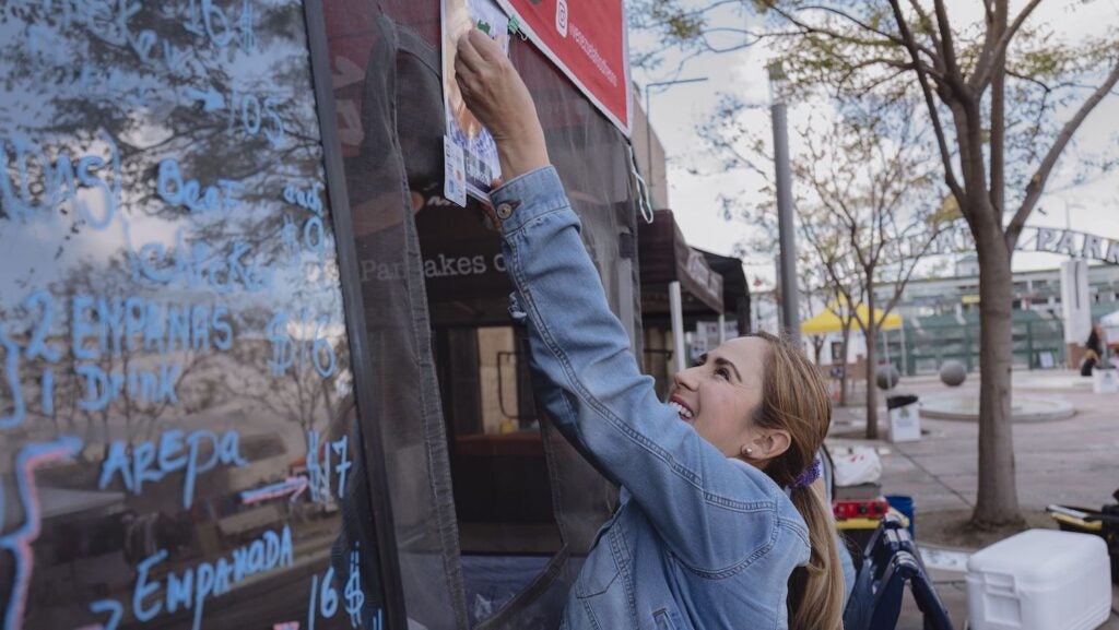 Woman putting up sign on food stand