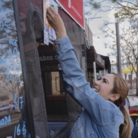 Woman putting up sign on food stand