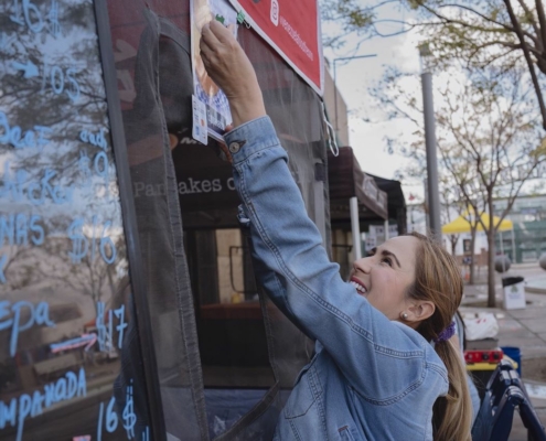 Woman putting up sign on food stand