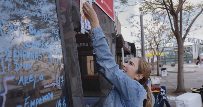 Woman putting up sign on food stand