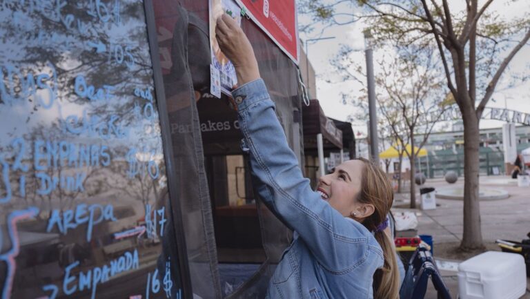 Woman putting up sign on food stand