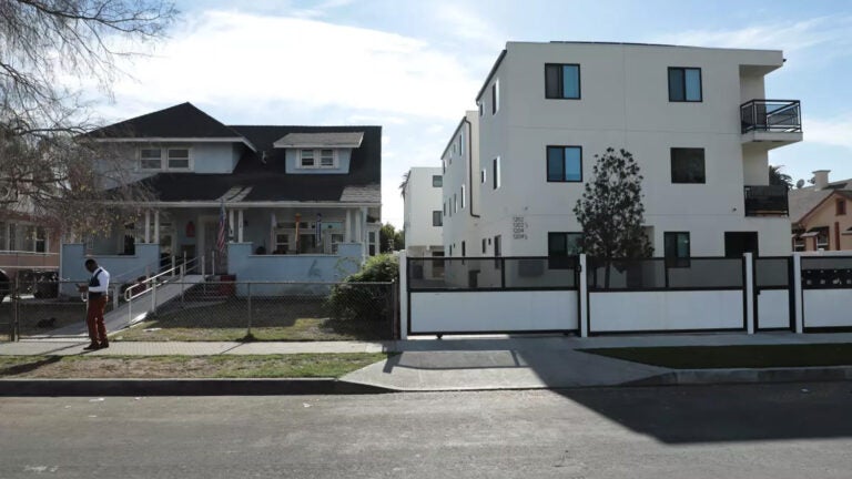 A single-story home sits next to a three-story apartment building