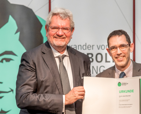 Two men holding paper folder holding award statement