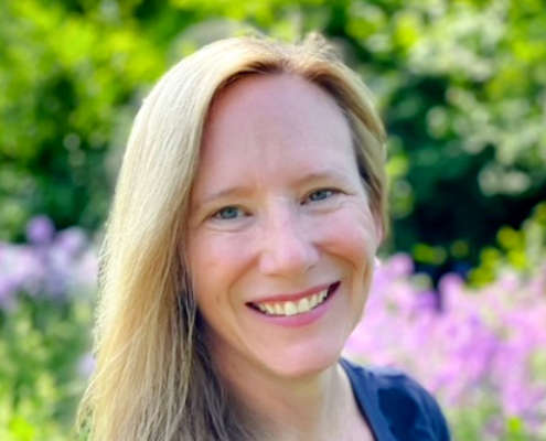 photo of woman with blond hair in front of flowering plants