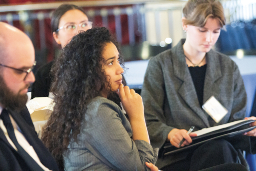 young woman with curly dark hair listens to speaker