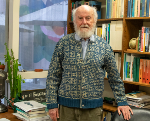 man with white beard in office with artwork behind him