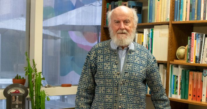 man with white beard in office with artwork behind him