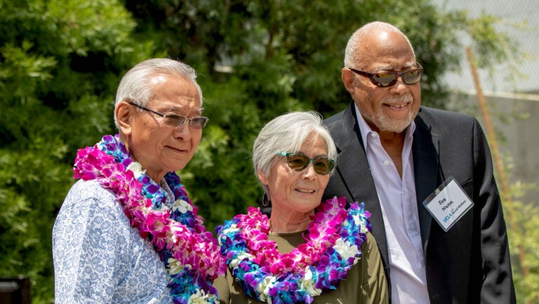 three people outdoors, two wearing leis|three young people in historic B&W photo