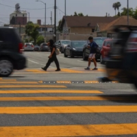 children in a crosswalk as cars speed by