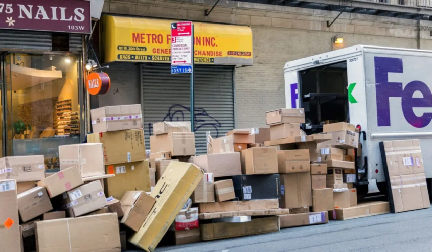 boxes piled behind a FedEx truck on a city street
