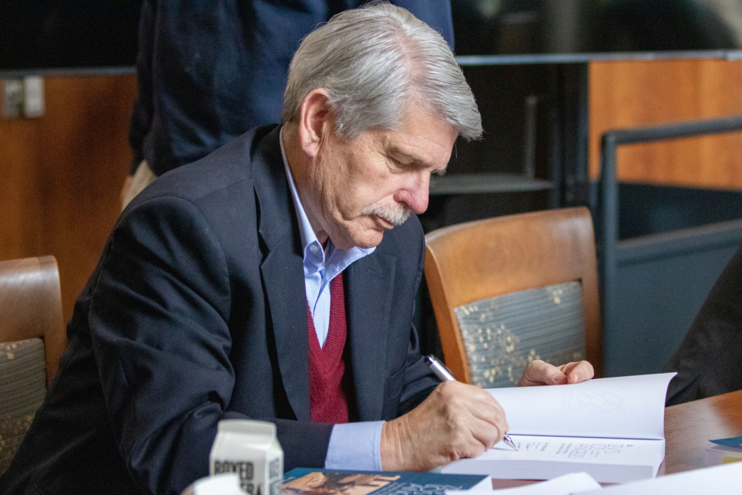 Man seated and autographing book