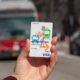 a hand holds a Mobility Wallet card as a bus approaches in the background