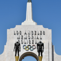 top of white building with spire and Olympic Games logo