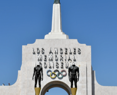 top of white building with spire and Olympic Games logo