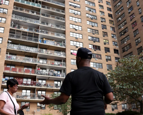 three people outside large apartment complex