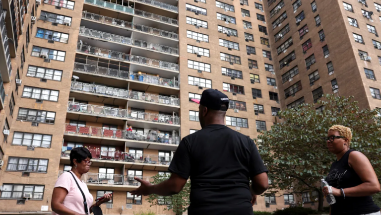 three people outside large apartment complex