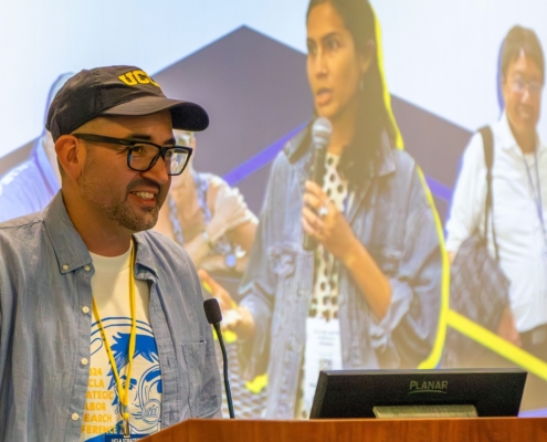 Man in ballcap at podium in front of screen