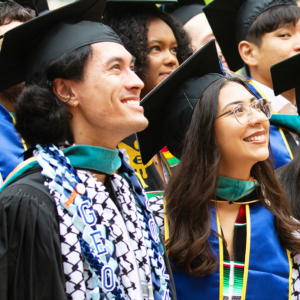 Graduates in caps and gowns smile and look off camera