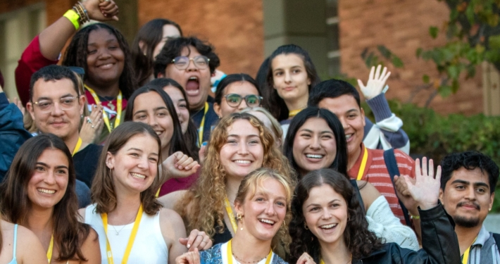 Group of students smiling and waving