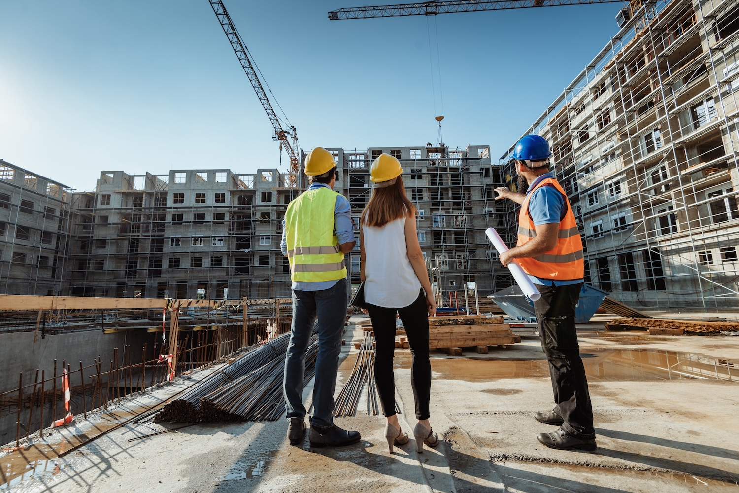 People working on construction site, wearing protective equipment and discussing next construction phase