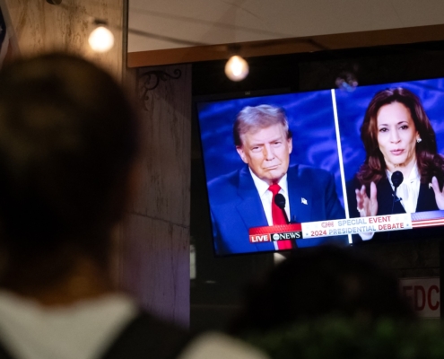 person watching television screen showing presidential candidates