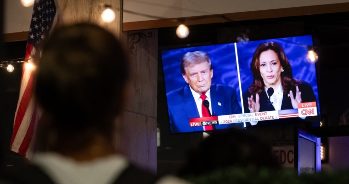 person watching television screen showing presidential candidates