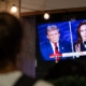 person watching television screen showing presidential candidates