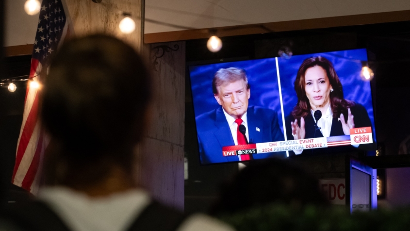 person watching television screen showing presidential candidates