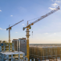 Cranes on the construction site surrounded by new real estates. Scenic aerial photo of growing city districts