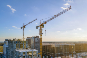 Cranes on the construction site surrounded by new real estates. Scenic aerial photo of growing city districts