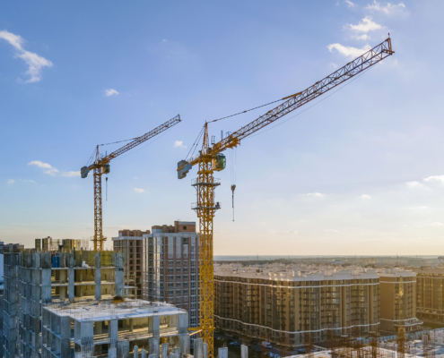 Cranes on the construction site surrounded by new real estates. Scenic aerial photo of growing city districts