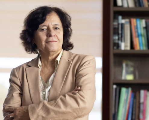 woman in tan suit next to bookcase